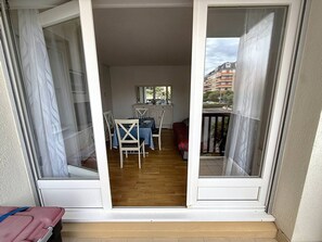 A balcony with a sliding glass door leading to a dining area with a table and chairs.