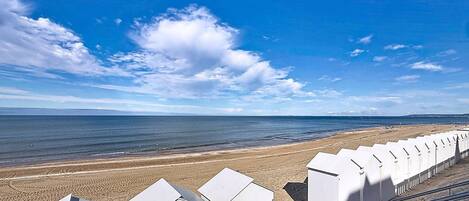 Een strand met een rij witte strandhutten en een helderblauwe lucht.