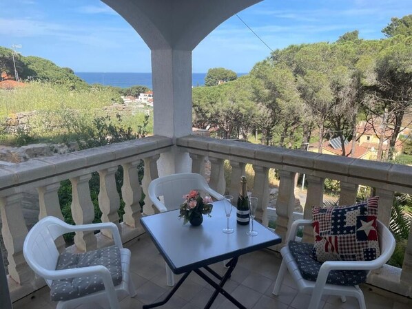 A balcony with a table, chairs, and a bottle of champagne.