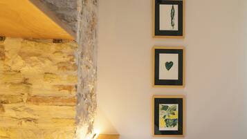 A room with a stone wall, a wooden beam, and three framed artworks on the wall.