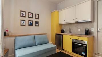 A compact living space with a sofa, kitchenette, and wall-mounted artwork.
