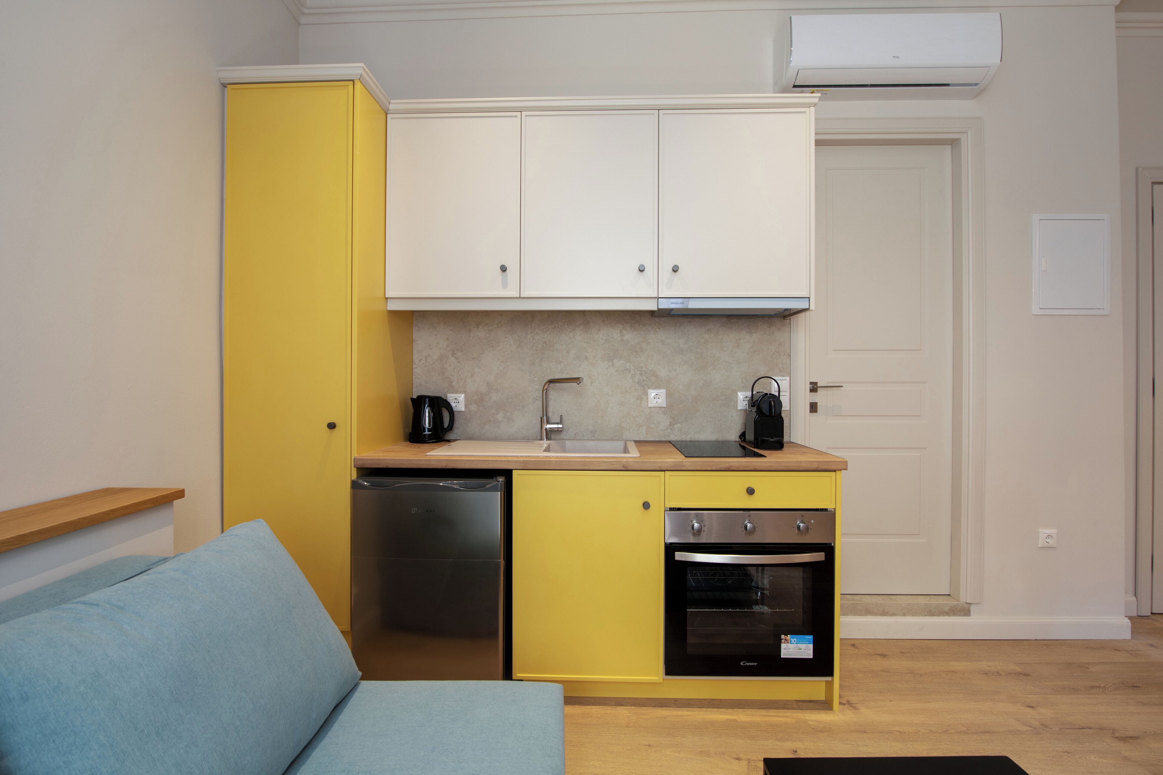 A compact kitchen with yellow cabinets, a dishwasher, an oven, and a coffee maker.