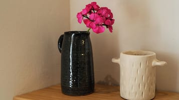 Un jarro de cerámica negra con asa y una taza de cerámica blanca con asa sobre una estante de madera.
