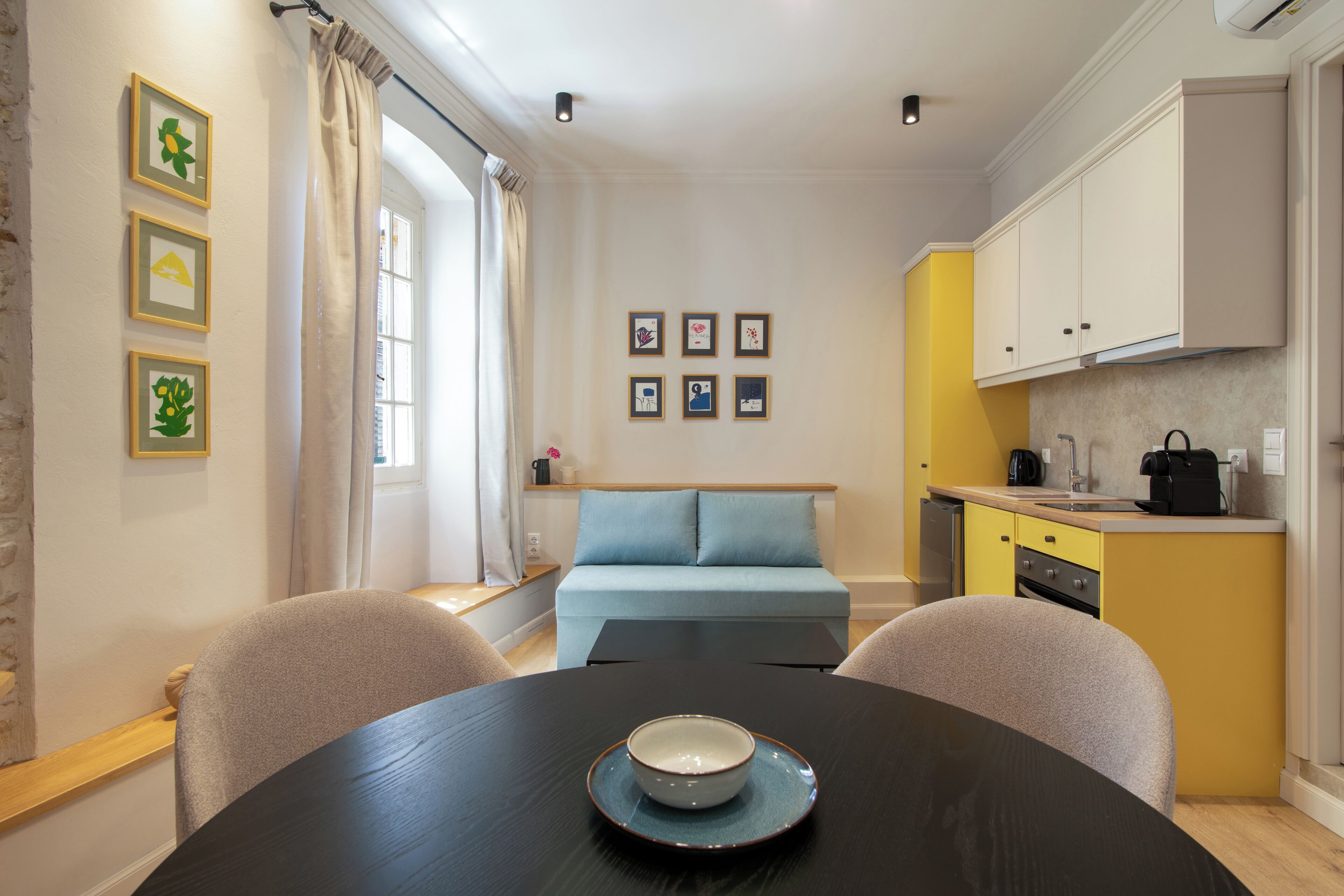 A compact living space with a dining table, a sofa, and a kitchenette.