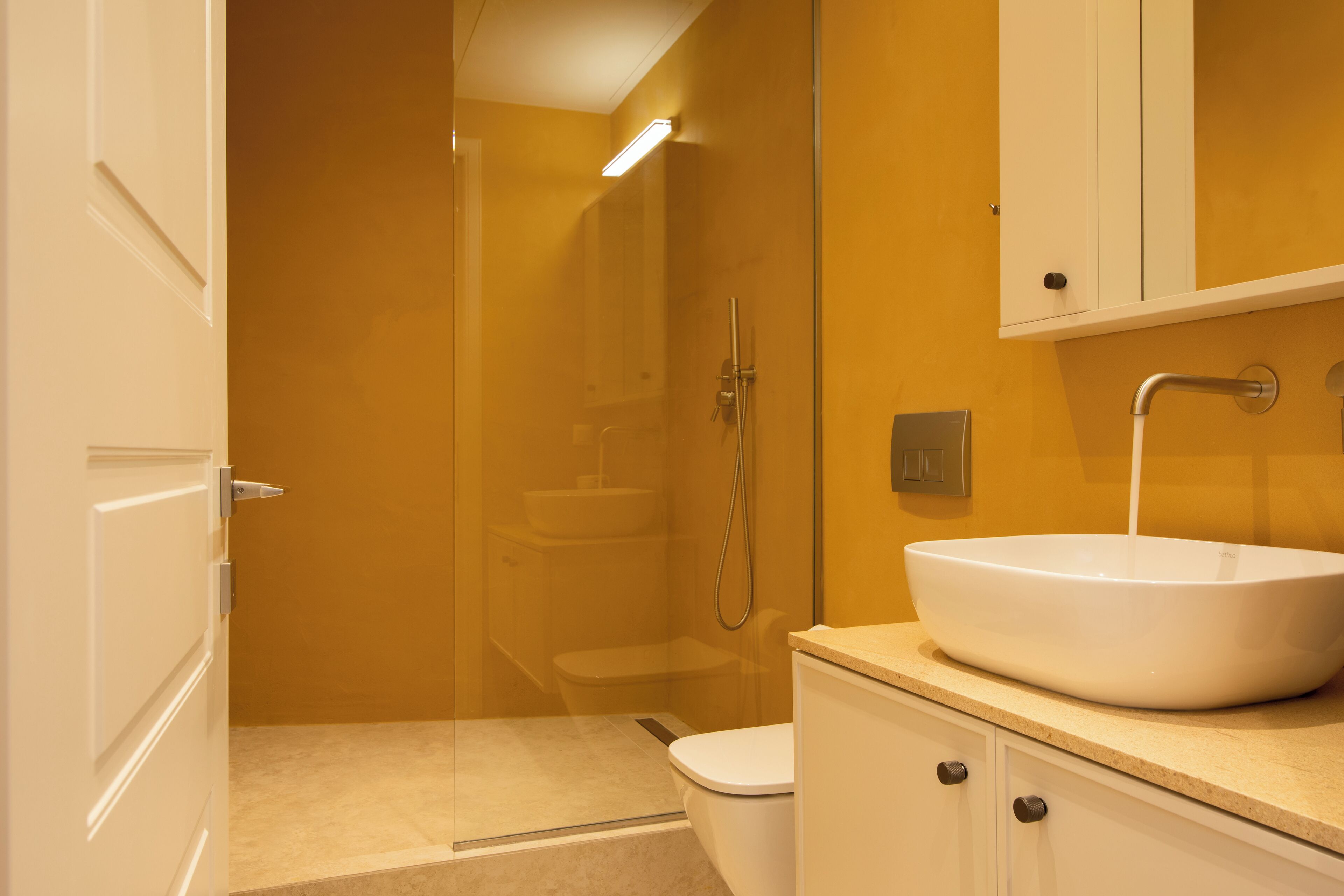 A bathroom with a glass shower enclosure, a white sink, and a toilet.