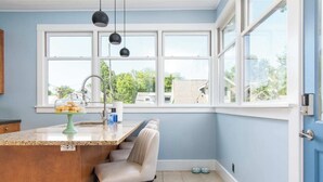 A kitchen with a large window, a countertop with a glass display case, and a chair.