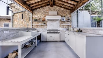 A kitchen with a stone wall, white cabinetry, and a large window.