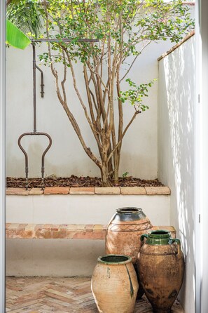 A corner with a tree, a metal structure, and two ceramic pots.
