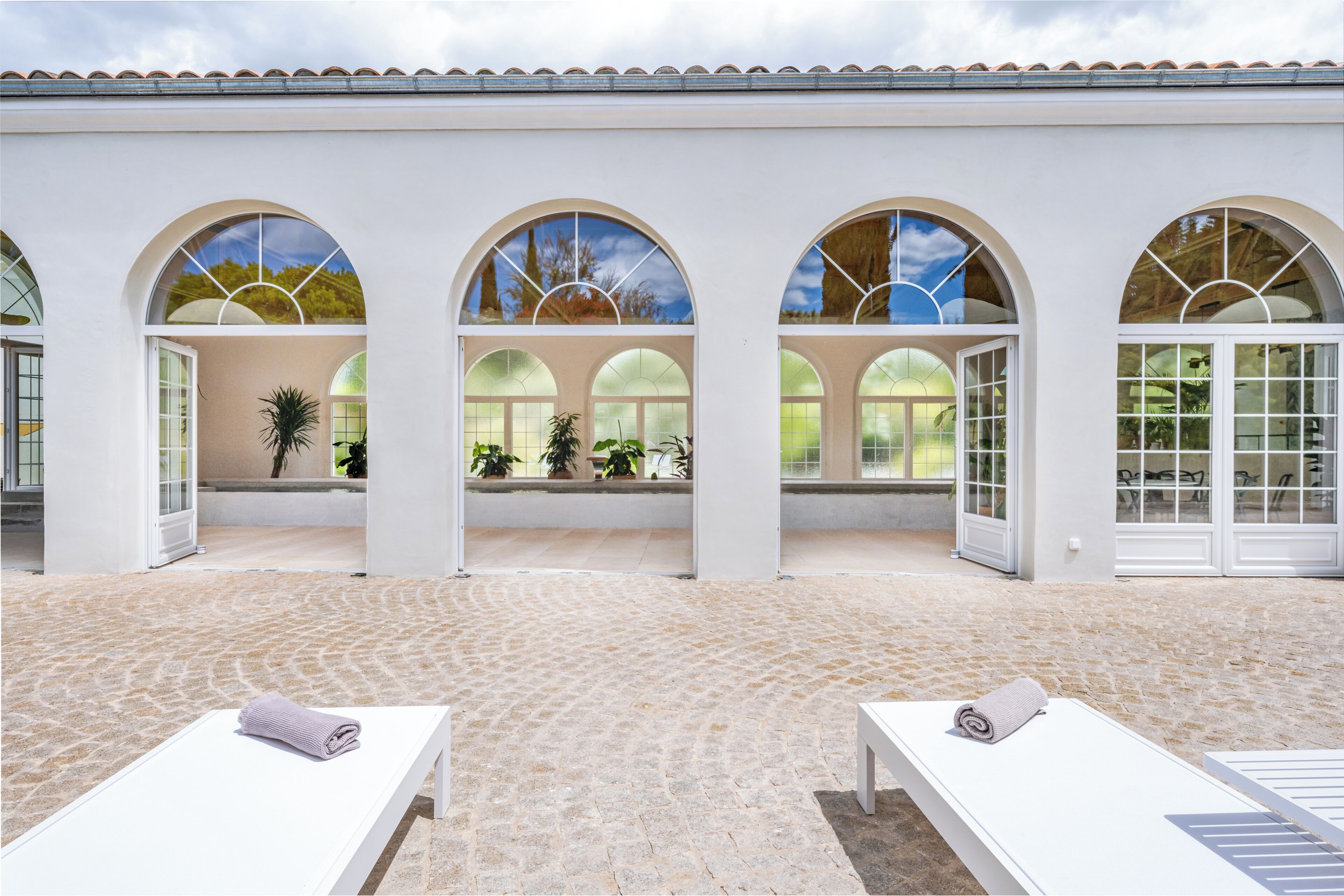 A spa area with three arched windows, a tiled floor, and two lounge chairs with towels.