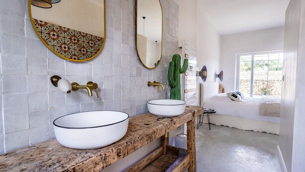 A bathroom with two white sinks, a wooden vanity, a mirror, and a cactus. - Domaine Secret d'Uzès & Spa: Le Duché, with a heated swimming pool (Aubussargues)