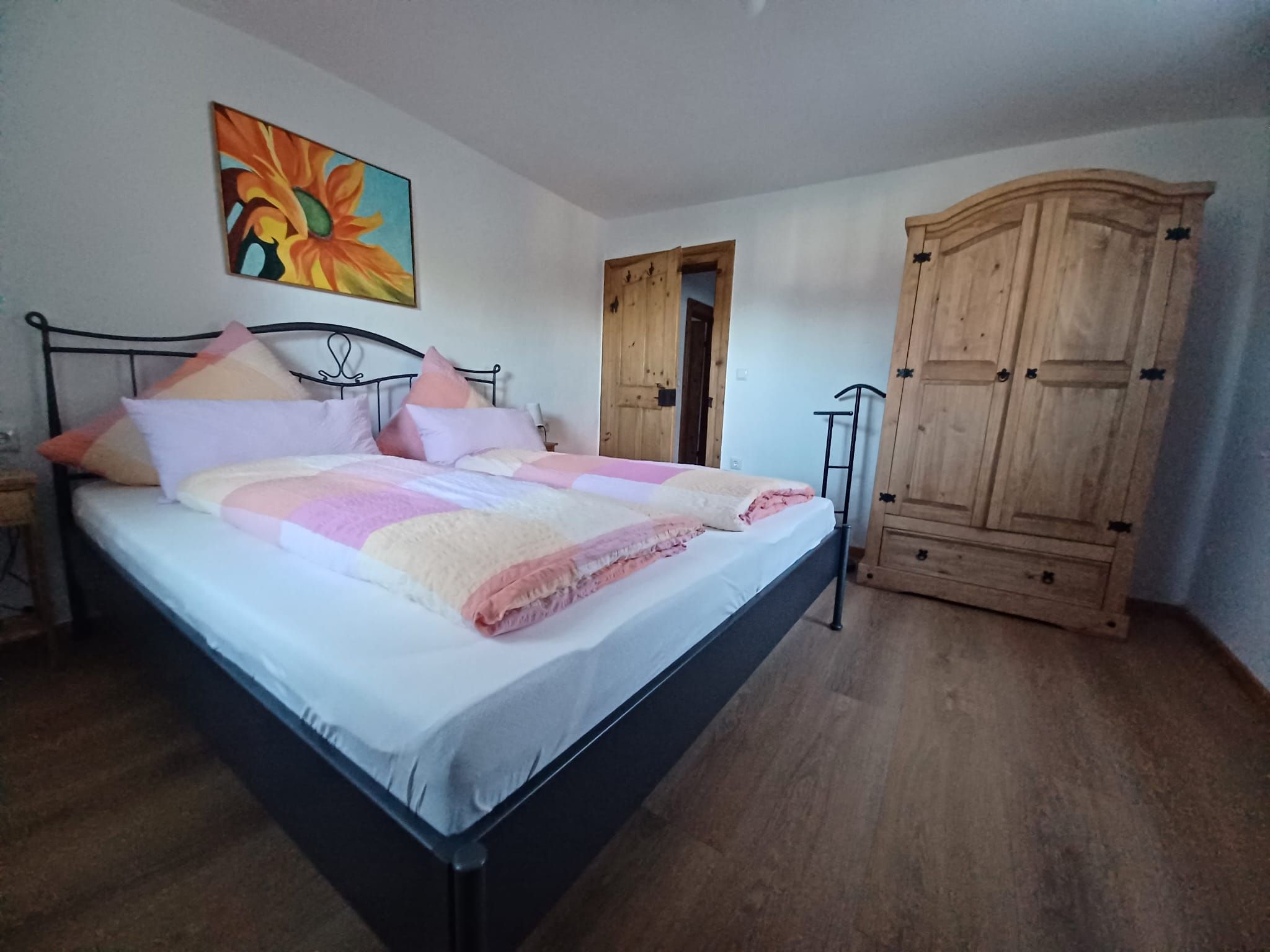 Ein Schlafzimmer mit einem Bett, einem Holzschrank und einem Gemälde an der Wand.