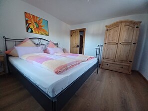 Une chambre à coucher avec un lit, une armoire en bois et un tableau accroché au mur.