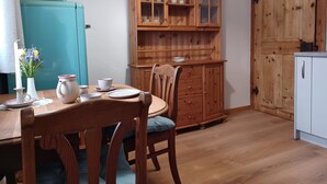 A dining area with a wooden table, chairs, and a cabinet with glass doors. - Feel-good place in the heart of Pfaffenwinkel:Freshly renovated with its own terrace (Rottenbuch)
