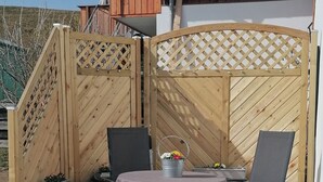 A wooden deck with a table and chairs, a metal bucket, and a small potted plant. - Feel-good place in the heart of Pfaffenwinkel:Freshly renovated with its own terrace (Rottenbuch)