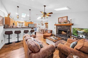 A spacious living area with a fireplace, a sofa set, a coffee table, and a television.