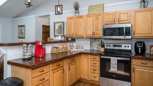 A kitchen with wooden cabinets, a microwave, a stove, and a coffee maker. - Cozy Nest Cabin at Coosawattee (Ellijay)
