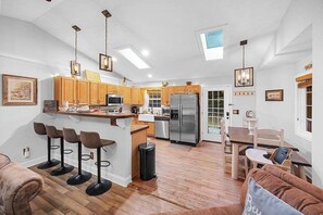 Une cuisine moderne dotée d’un îlot central, de tabourets de bar et d’un coin repas avec une table et des chaises.