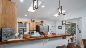 A modern kitchen with a wooden countertop, bar stools, and a sign that reads "Be a nice Human." - Cozy Nest Cabin at Coosawattee (Ellijay)