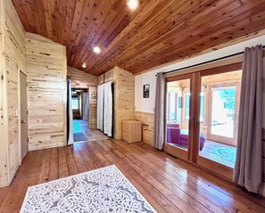 A wooden interior with a hallway leading to a room with a sliding glass door. - Serenity POW! ~ Indoor Hot Tub (WINTER ONLY)~ 3 Private Acres! (Bessemer)