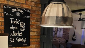 A dining area with a brick wall, a blackboard with text, a table set for two, and a modern pendant light.