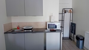 Cocina compacta con microondas, lavamanos y un refrigerador pequeño.