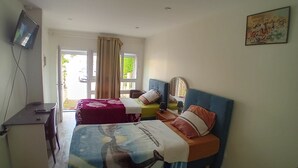 Un dormitorio con dos camas, un escritorio, un televisor y una ventana con cortinas.