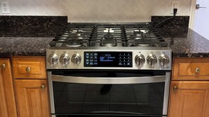 A kitchen with wooden cabinets, a stainless steel microwave, a gas stove, and an oven.