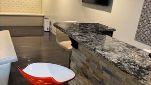 A modern kitchen with a marble countertop, a built-in oven, and a stone backsplash.