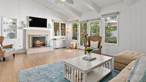 A spacious living room with a fireplace, a ceiling fan, and large windows. - Across the street from the beach with Pool and Spa (Solana Beach)