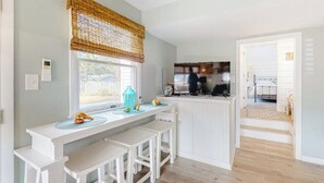 A kitchen with a white countertop, a window with a bamboo blind, and a view of the backyard.