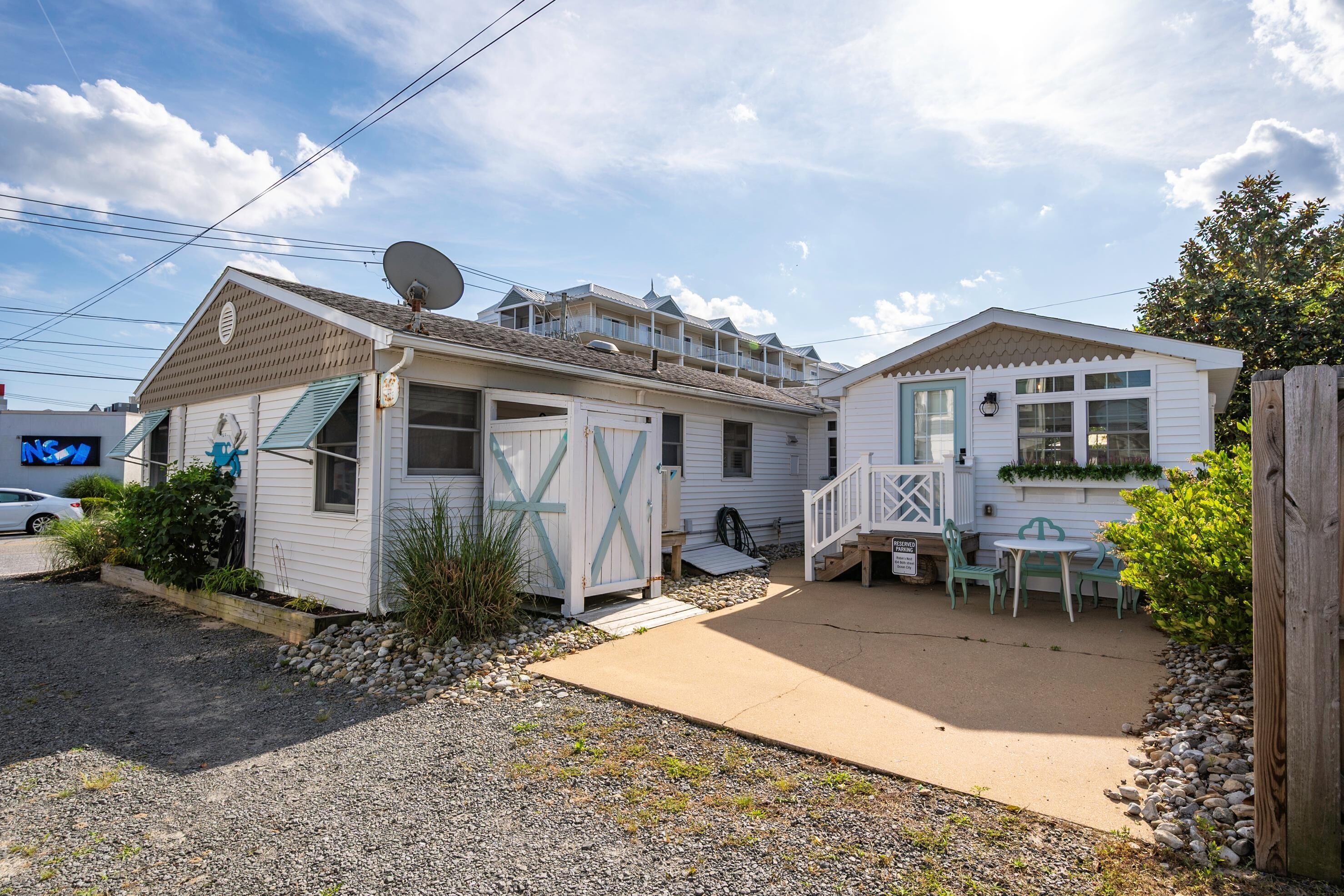 A white mobile home with a covered patio, a satellite dish, and a small deck.