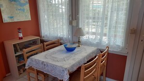 Zona de menjador amb taula coberta amb una feinçana de punt de gots, envoltada de cadires de fusta.