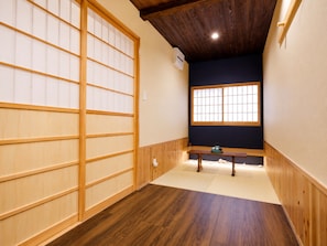 A traditional Japanese room with tatami flooring, a sliding door, a window with a view, and a bench. - Nara-Ryokan Villa (Nara)