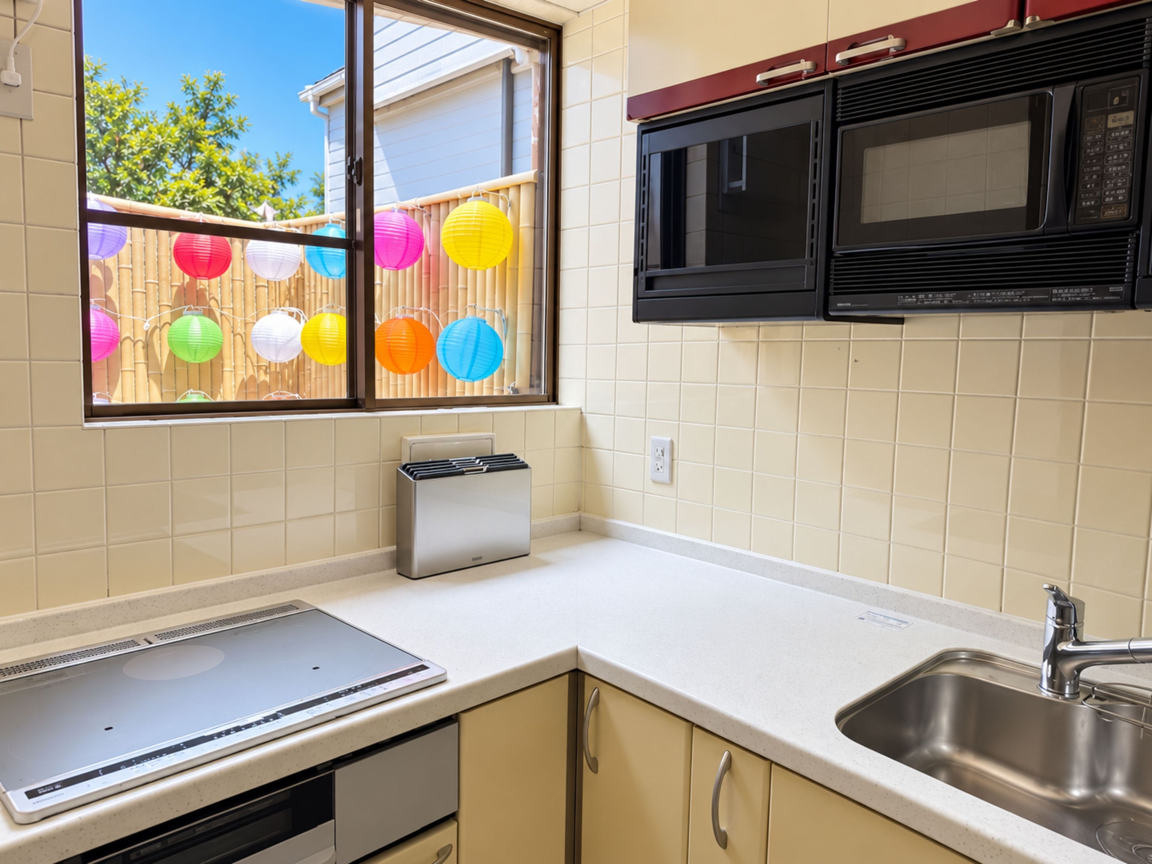 A kitchen with a microwave, toaster, and a window with colorful paper lanterns.