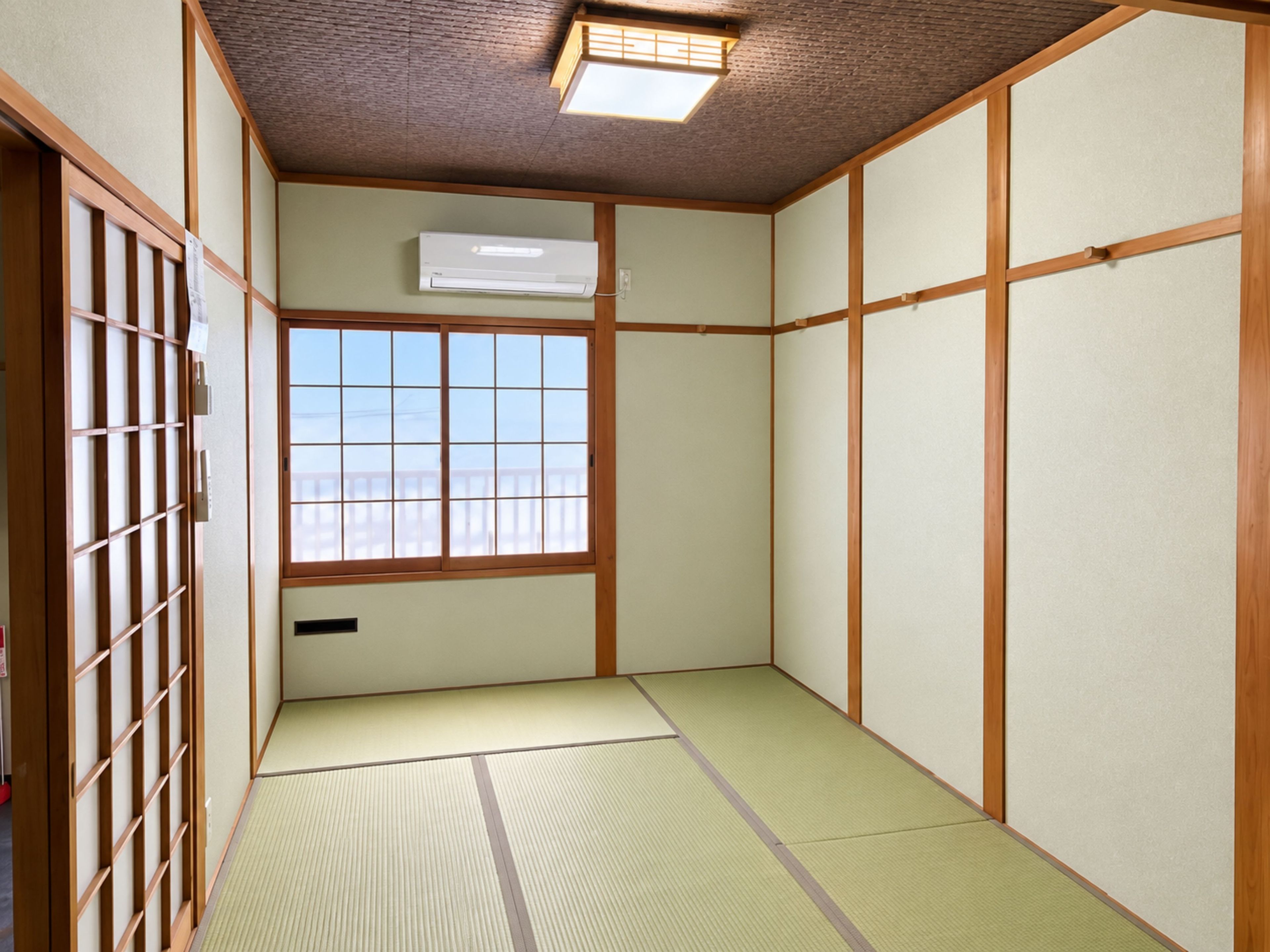 A traditional Japanese room with tatami flooring, shoji screens, and a sliding door.