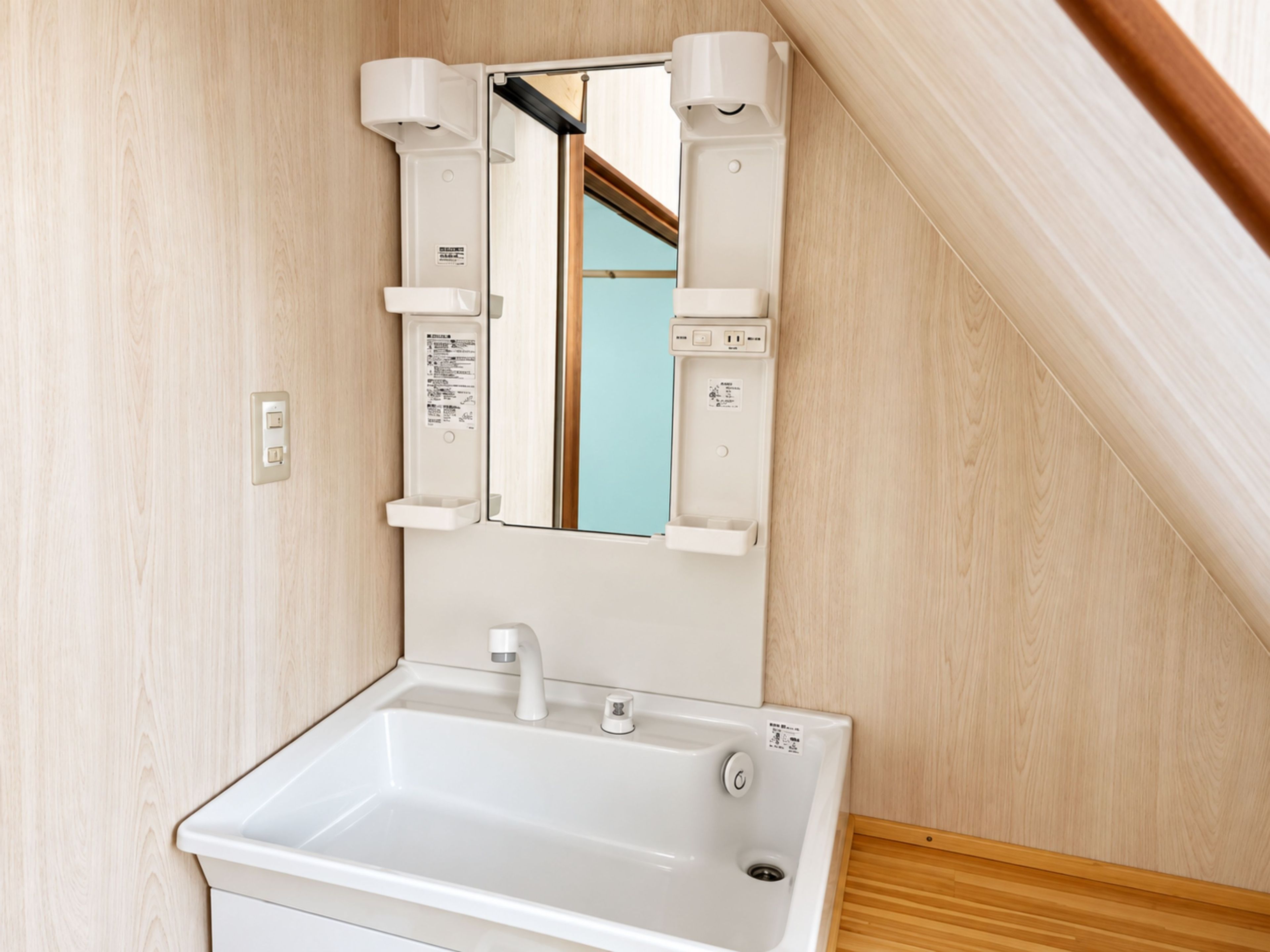 A bathroom with a white sink, mirror, and towel dispenser.