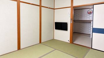 A traditional Japanese room with tatami flooring, a television mounted on the wall, and a sliding door with a Mickey Mouse design.