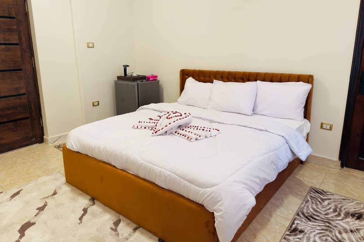A bedroom with a bed, a wooden headboard, a nightstand, and a door.