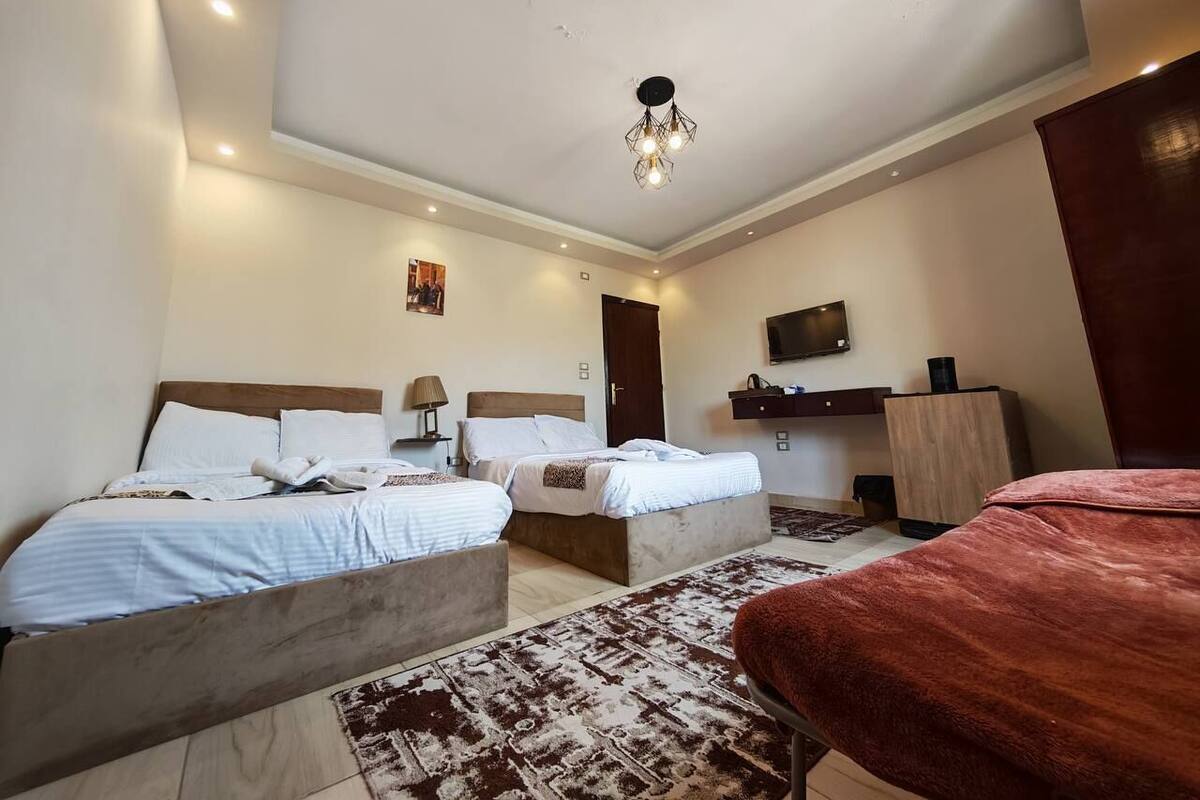 A hotel room with two beds, a TV, a desk, and a wardrobe.