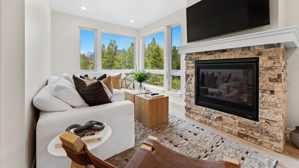 Una sala de estar moderna con chimenea de piedra, ventanas amplias y un televisor de pantalla plana.