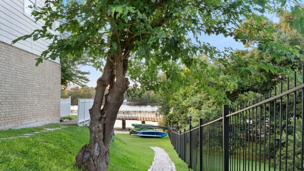 A tree-lined pathway leading to a body of water with boats.