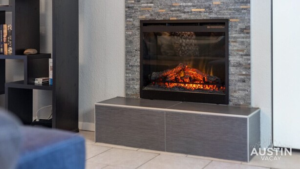 A modern fireplace with a stone facade and a built-in entertainment unit to the left. - Ravey #B xxxxxxxxxxx (Austin)