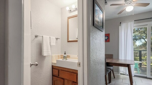 Un baño con tocador de madera, un espejo y un perchero para toallas.