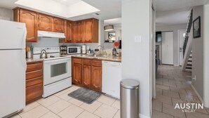 A modern kitchen with wooden cabinets, white appliances, and a tiled floor. - Ravey #B xxxxxxxxxxx (Austin)