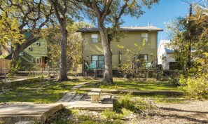 A residential area with a two-story house, a fenced yard, and a stone bench. - Ravey #B xxxxxxxxxxx (Austin)