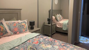 Ein Schlafzimmer mit Bett, Nachttisch, Spiegel und Kommode.