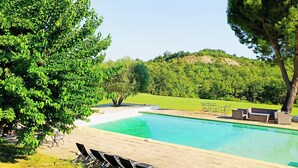 Une piscine avec des chaises longues et une pelouse.