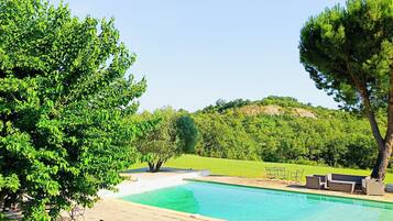 Piscina com espreguiçadeiras e área gramada.