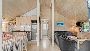 A modern kitchen with wooden cabinets, a refrigerator, and a dining area with a table and chairs. - Cozy home in Fårvang with WiFi (Fårvang)