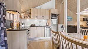 A modern kitchen with wooden cabinets, stainless steel appliances, and a dining area with a wooden table and chairs. - Cozy home in Fårvang with WiFi (Fårvang)